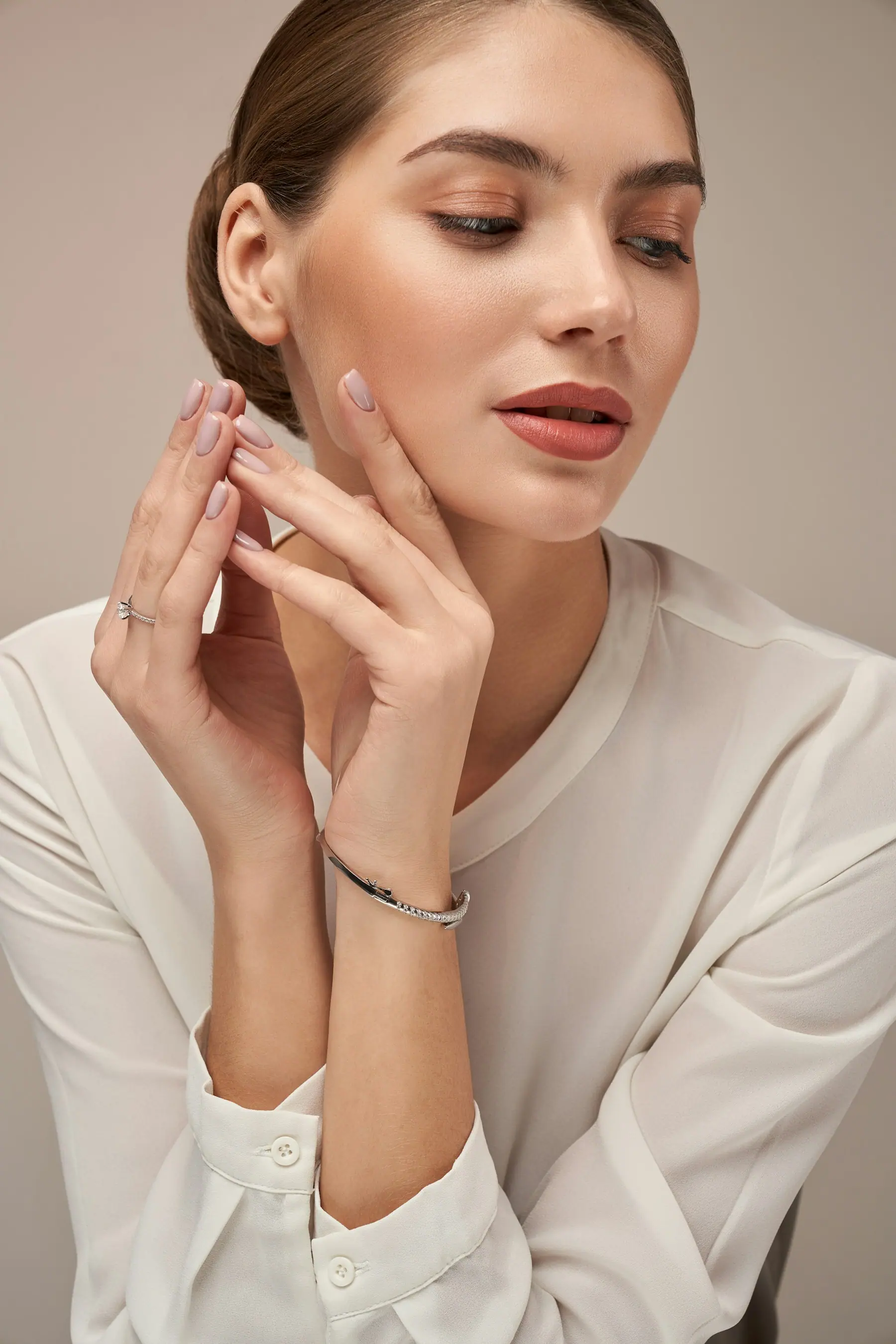 A fine rolled gold bracelet and rings worn with a soft white shirt