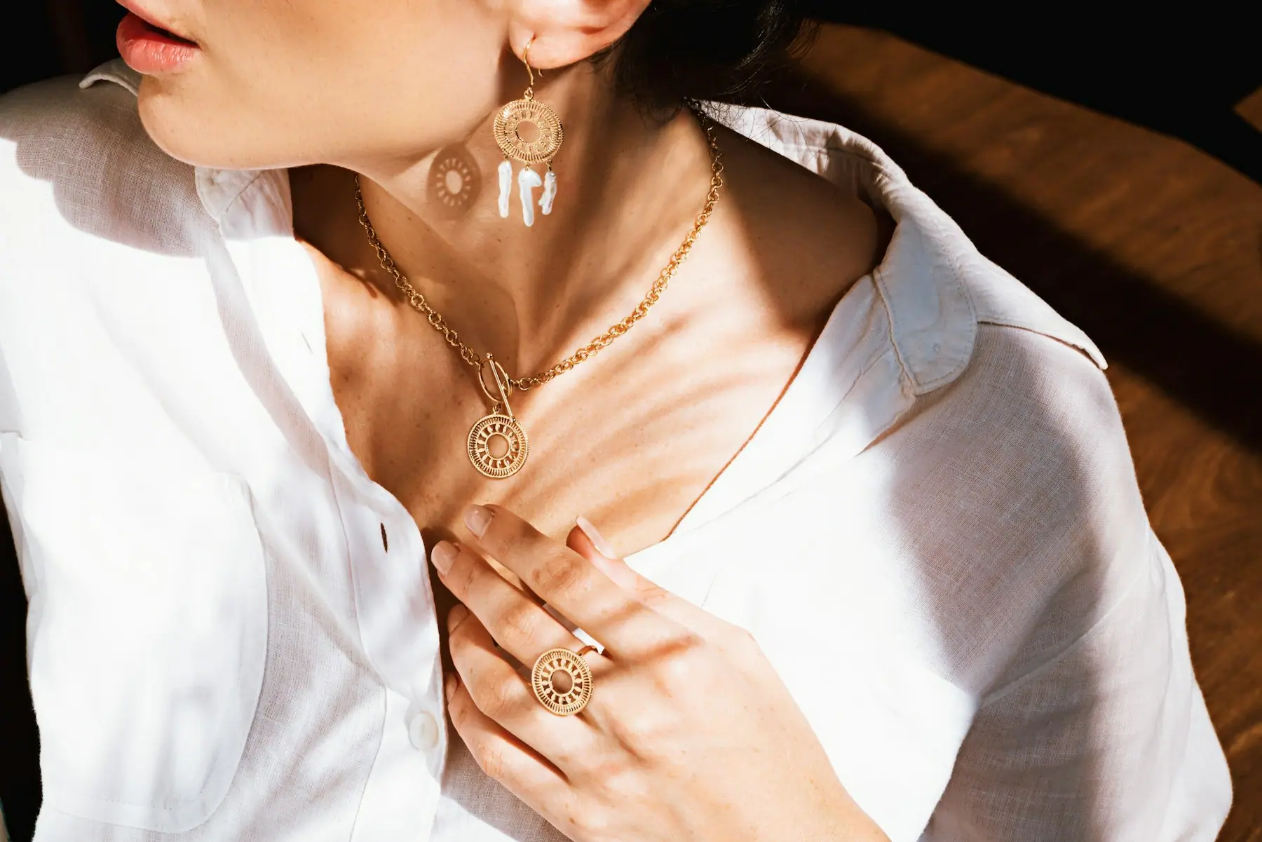 Layered rolled gold chains worn with an open-collar white shirt