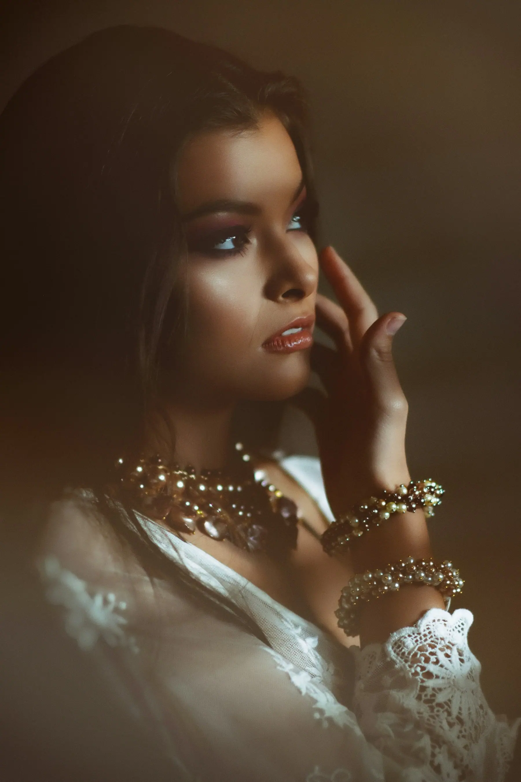 A model wearing layered rolled gold jewellery, photographed in low, warm light