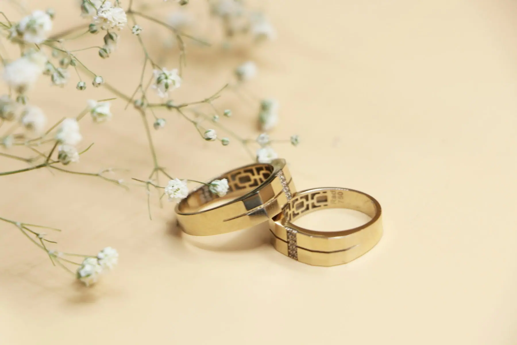 Fine rolled gold bands beside delicate white flowers