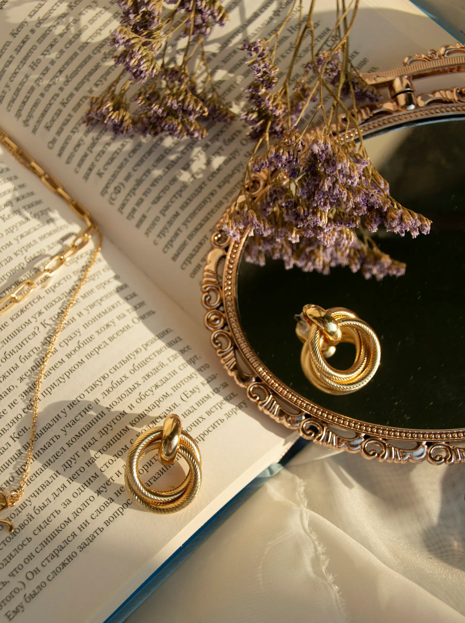 Gold hoop earrings and a fine chain resting on an open book