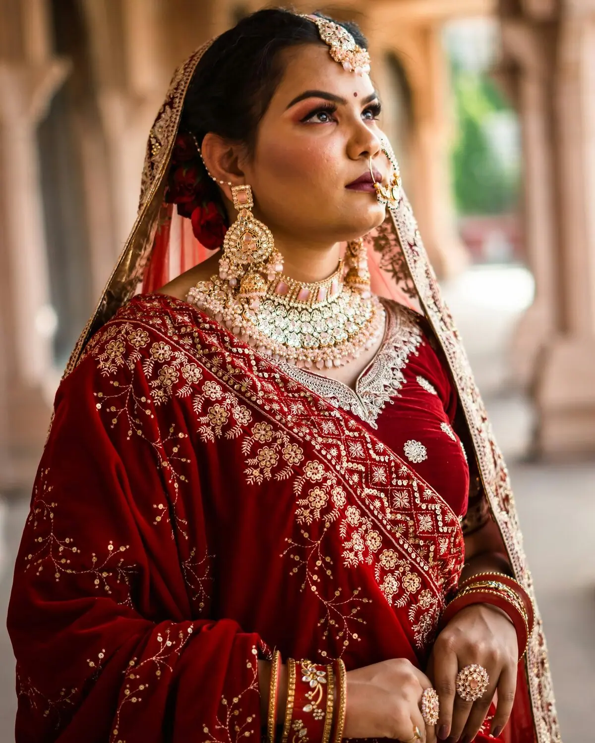 A temple collar and long jhumkas worn with a deep red occasion saree