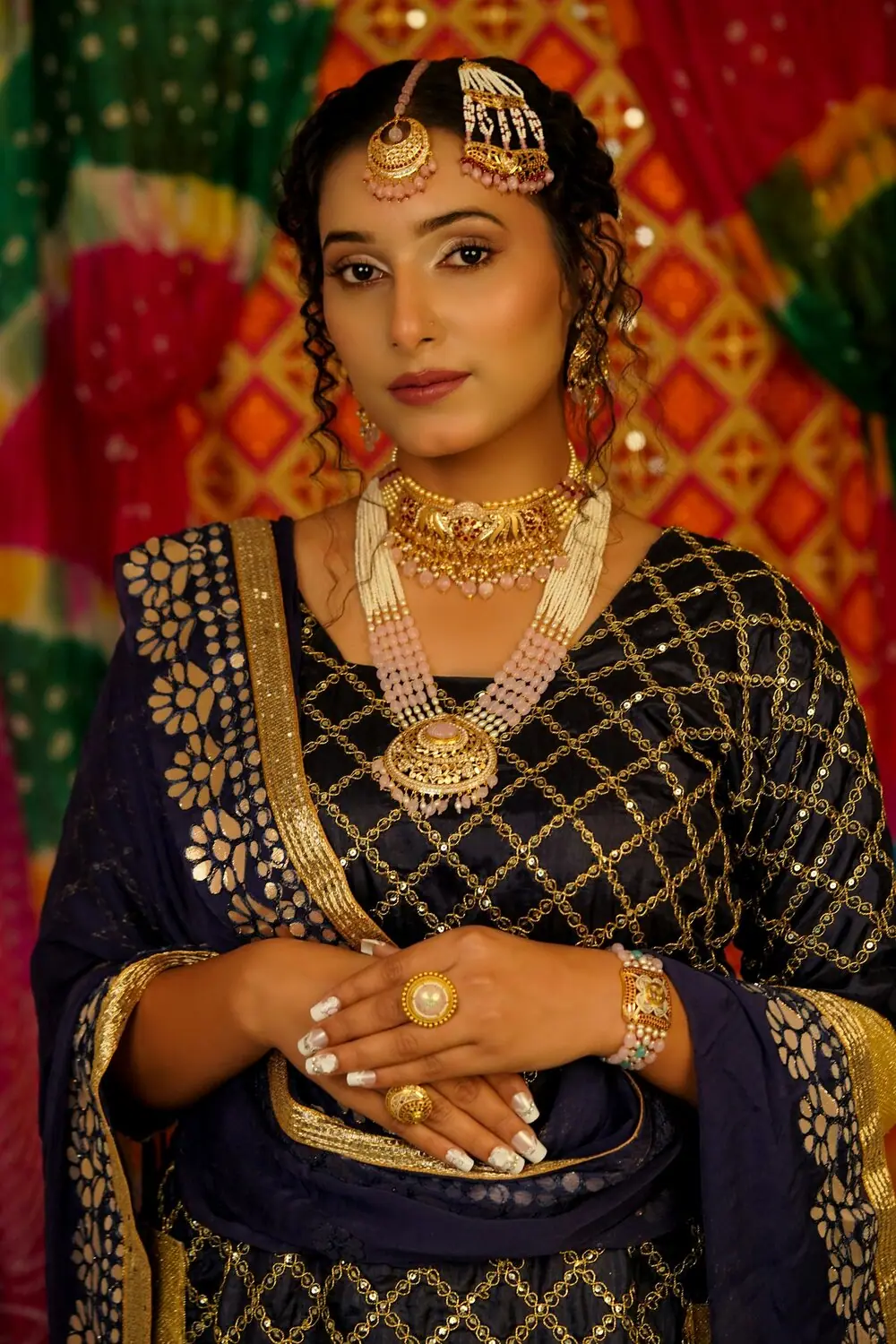 Several rolled gold chains of different lengths layered together over a dark silk blouse