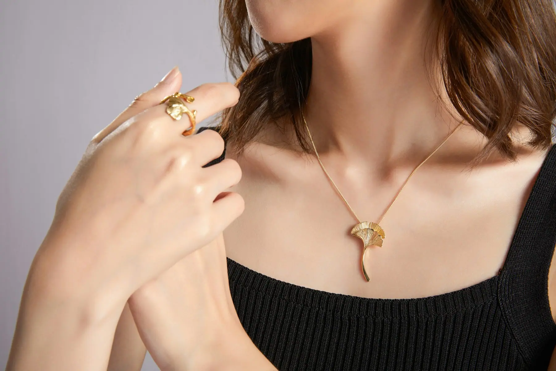 A fine rolled gold pendant worn with a black knit top