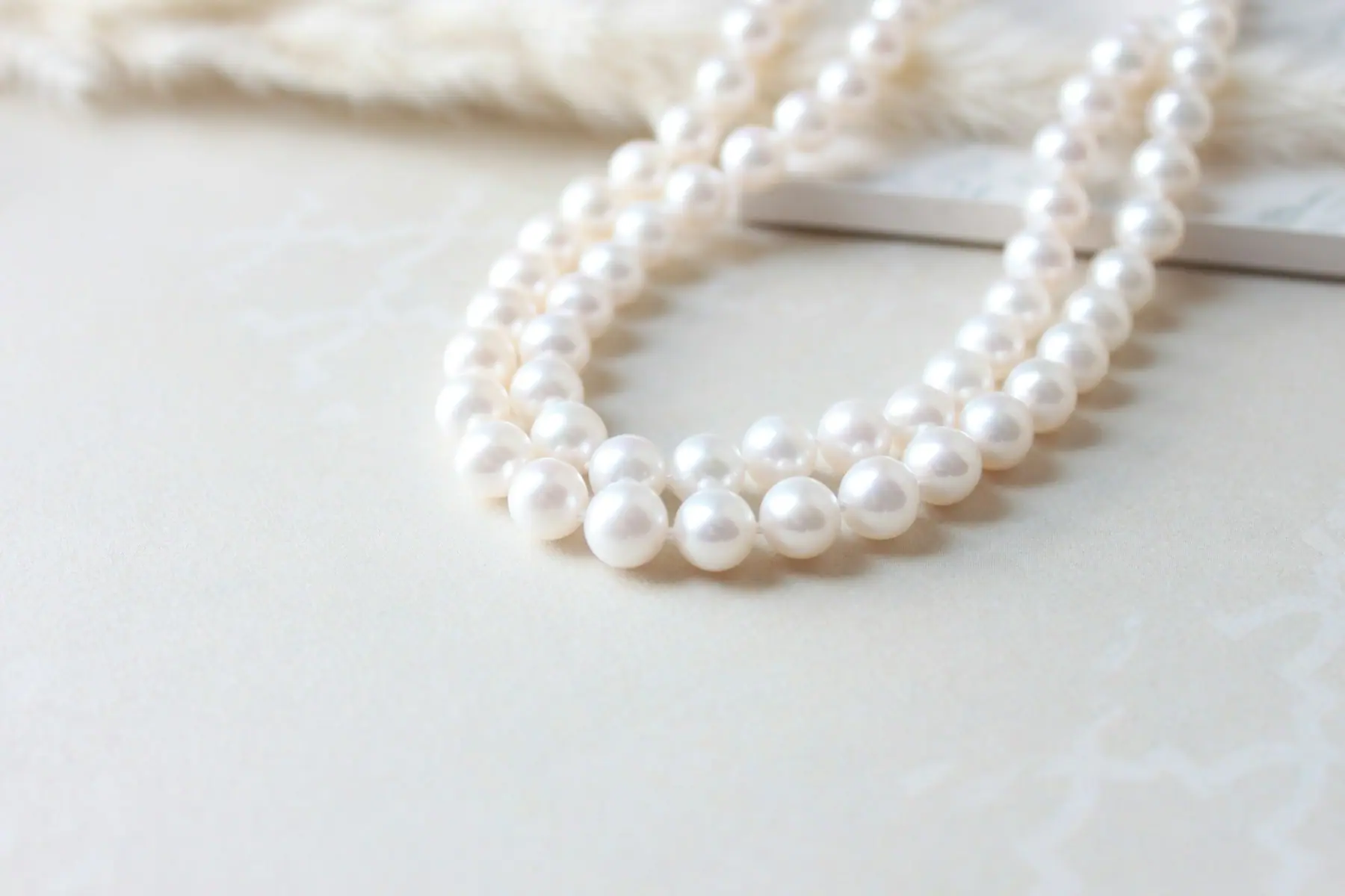 A graduated pearl strand coiled on ivory paper