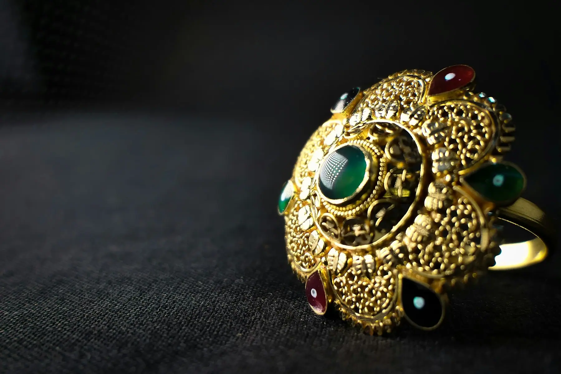 An ornate gold temple ring set with a green stone